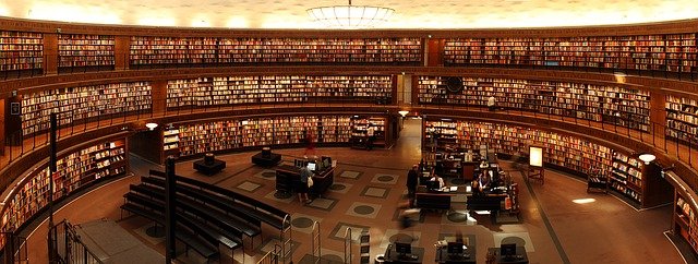 Książki - dziedzictwo wiedzy i kultury Stos starych książek na drewnianej półce w bibliotece.