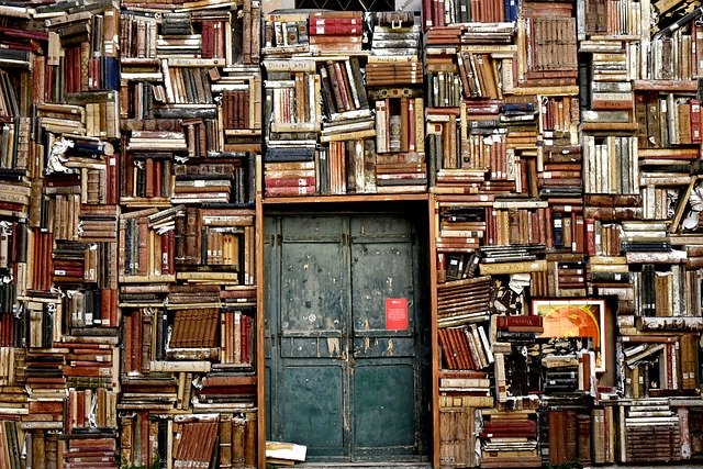 Dostęp do e-booków i zasobów online w bibliotece Osoba sięgająca po książkę z wysokiego regału w bibliotece.